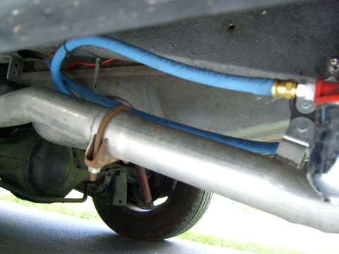 1972 Ford Ranchero - A close-up view of the undercarriage of a vehicle, focusing on the exhaust system and a blue fuel line.