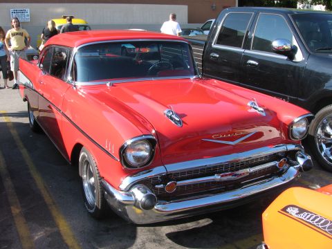 1990 Ford Bronco - bright red 1957 Chevrolet Bel Air with chrome bumper and Chevrolet hood script parked at an outdoor car show.