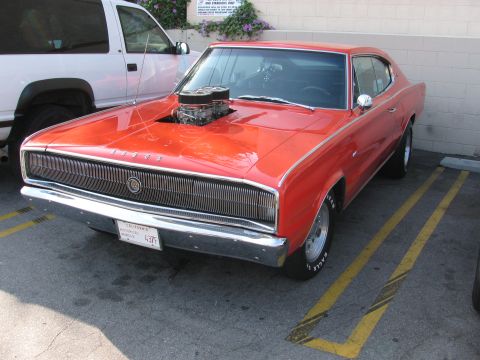 1990 Ford Bronco - red first-generation Dodge Charger with a hood scoop exposing the carburetor sits in a parking lot.