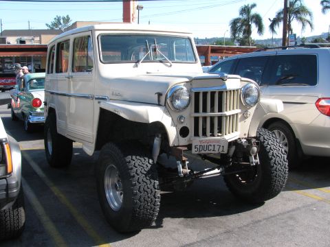 1990 Ford Bronco - white Willys Jeep station wagon lifted on chunky off-road tires sits in a lot, wearing California plate 5DUC171.