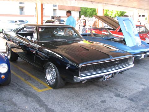 1990 Ford Bronco - black second-generation 1968 Dodge Charger with hidden headlights and Coke-bottle body parked at a car show.