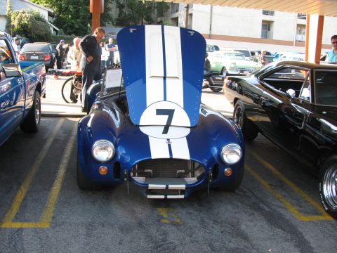 1990 Ford Bronco - blue Shelby Cobra-style roadster with white racing stripes and the number 7 on its hood, shown from the front.