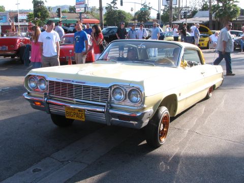 1990 Ford Bronco - pale yellow 1964 Chevrolet Impala with chrome trim and wire wheels parked at a street car show, plate BIGPAGE.