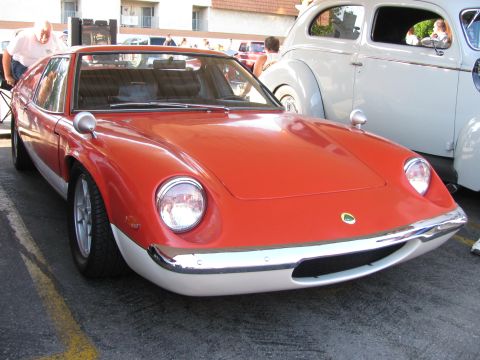 1990 Ford Bronco - red Lotus Europa wedge-profile sports car with its green and yellow Lotus nose badge parked at a car show.