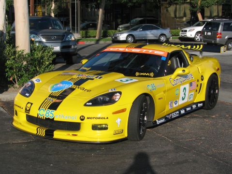 1990 Ford Bronco - yellow Chevrolet Corvette C6 race car wearing number 3, Compuware and E85 ethanol livery, parked on a street.