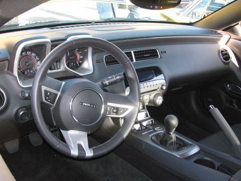 1990 Ford Bronco - gray interior of a fifth-generation Chevrolet Camaro showing the steering wheel, dual gauges and manual shift lever.