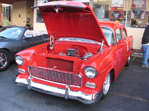 1990 Ford Bronco - red 1955 Chevrolet two-door with its hood raised, showing a chromed engine and chrome grille, parked at a show.