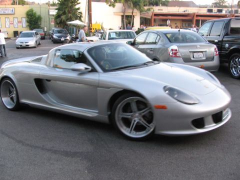 1990 Ford Bronco - silver Porsche Carrera GT roadster with top off, parked among other cars at an outdoor automotive gathering.