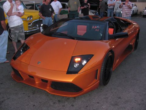 1990 Ford Bronco - orange Lamborghini Murcielago roadster parked at a nighttime car meet with spectators gathered behind it.