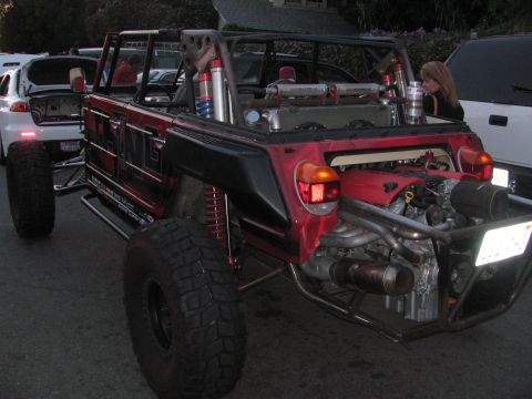 1990 Ford Bronco - red and black custom tube-chassis off-road buggy with coilover shocks and a mid-mounted engine, parked on a street.