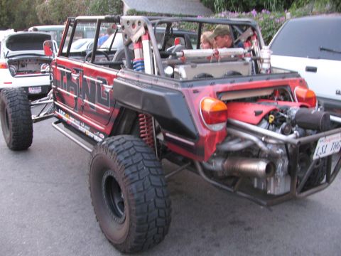 1990 Ford Bronco - rear of a red custom tube-chassis off-road buggy showing its exposed engine, exhaust and big mud tires.
