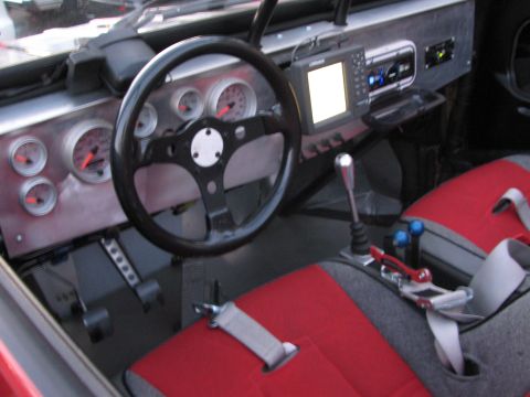 1990 Ford Bronco - interior of a custom off-road buggy with an aluminum dash, round gauges, digital display and red bucket seats.