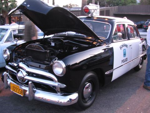 1990 Ford Bronco - black-and-white Burbank Police vintage Ford sedan displays its engine bay with hood open and roof beacon.