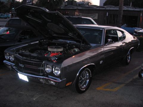 1990 Ford Bronco - brown Chevrolet Chevelle SS coupe sits with hood raised exposing its engine at an evening car show.