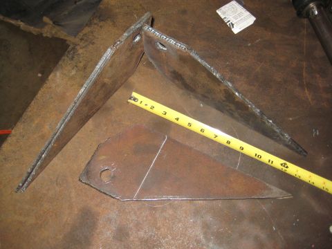 1990 Ford Bronco - Welded metal brackets and a tape measure are shown on a workbench surface.