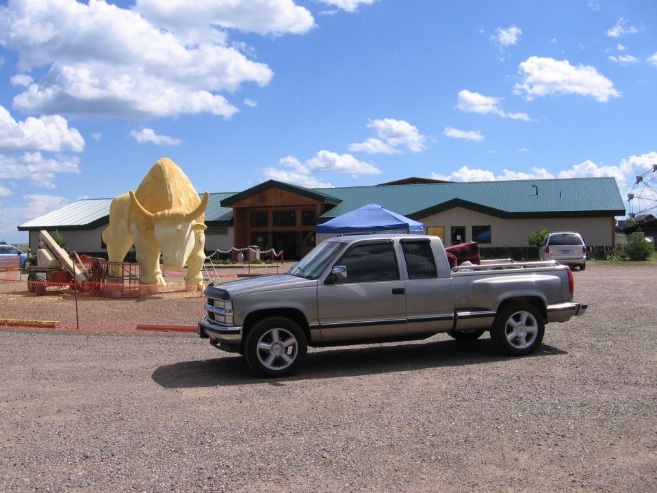 Silver pickup truck parked in front of a building with a large bison statue