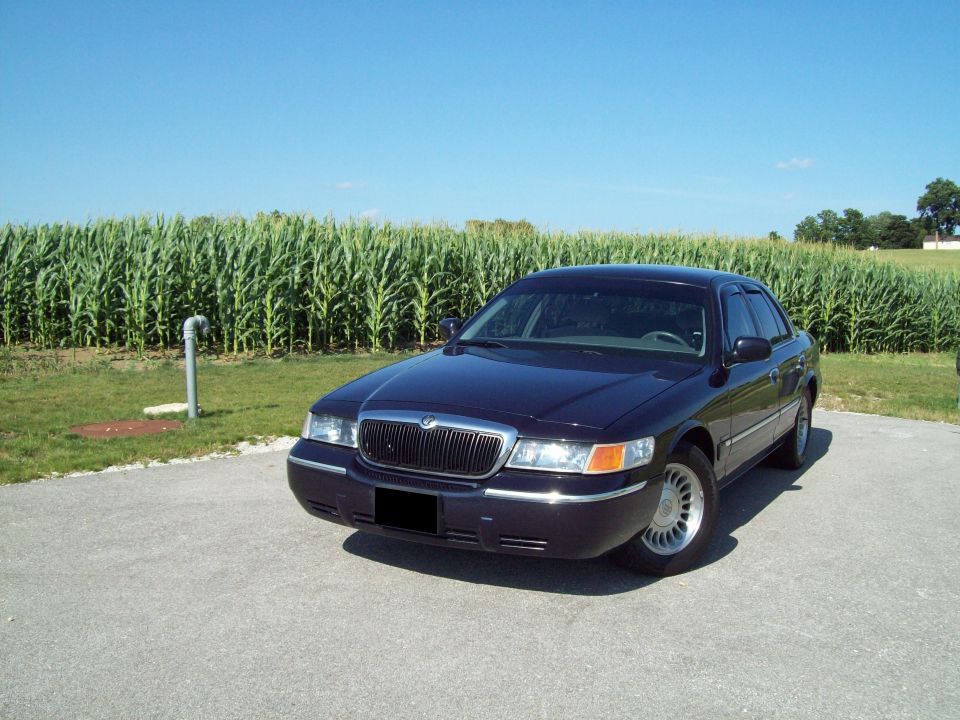 Dark blue Mercury Grand Marquis sedan parked in front of a cornfield