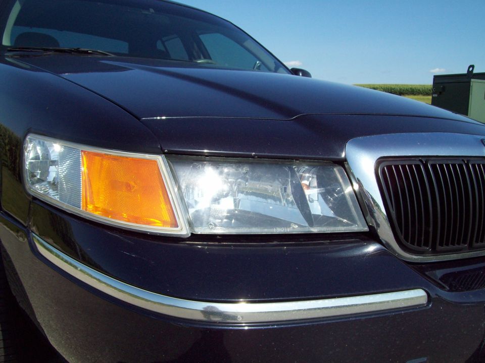 Front corner close-up of a dark blue Grand Marquis showing grille, headlight and amber marker
