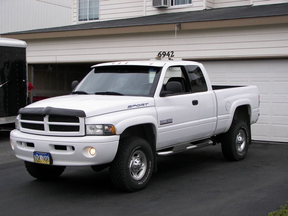 White pickup truck with a black bug deflector and a "SPORT" decal on the fender