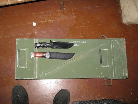 2000 Mercury Grand Marquis - Two knives are placed on a green metal box with some markings, and a person's feet are visible at the bottom of the frame.