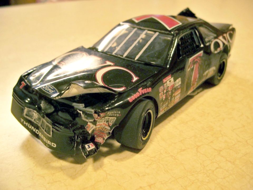 Damaged toy Ford Thunderbird race car with "C" logo and "7" on door