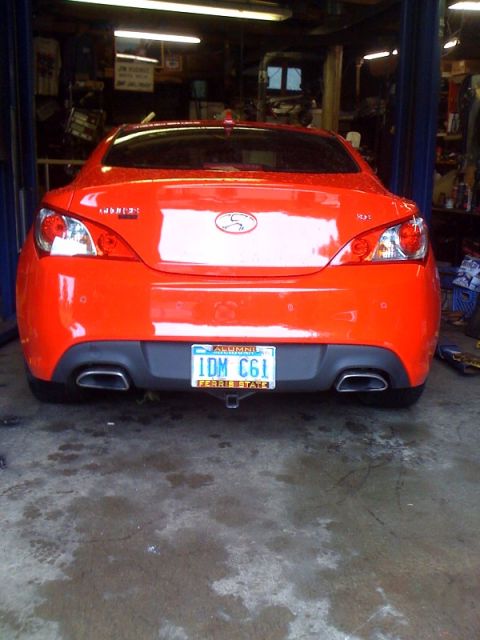 2010 Hyundai Genesis - The rear of an orange Hyundai Genesis coupe is shown in a garage setting with its license plate visible.