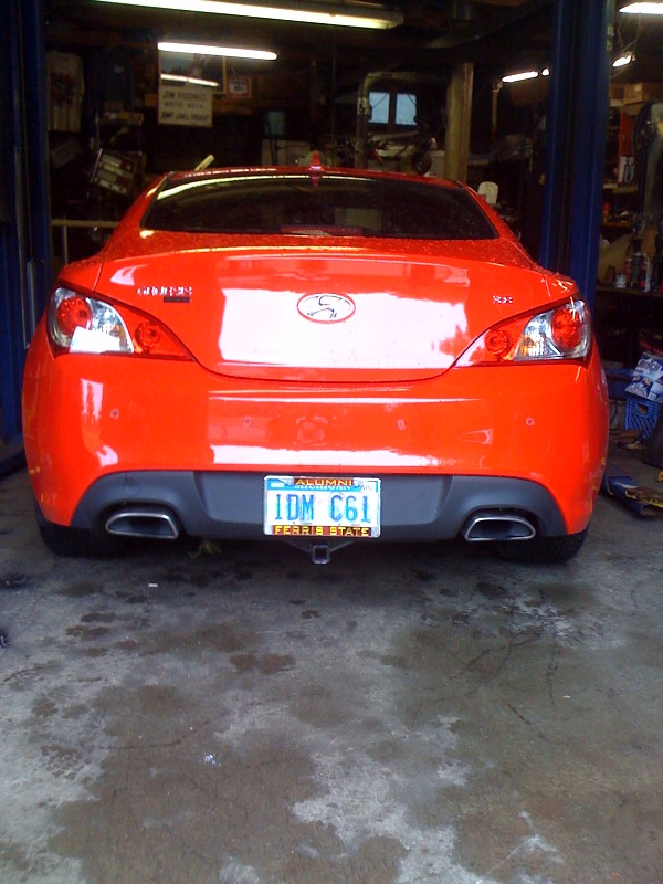 Rear of a red Hyundai Genesis Coupe in a garage with dual exhaust tips