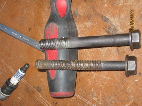 1994 Ford Bronco - A close-up view of automotive parts, including bolts and a spark plug, on a workbench.