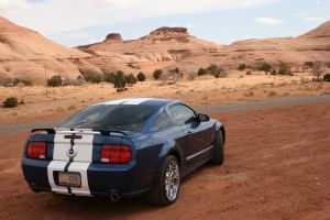1993 Ford Taurus - Blue Ford Mustang with racing stripes parked in a desert landscape.