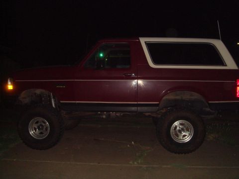 1992 Ford Bronco - Side view of a lifted 1992 Ford Bronco with a two-tone paint scheme, photographed after dark.