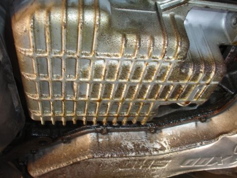 1993 Ford Taurus - Close-up view of a dirty oil pan with a distinctive grid pattern.