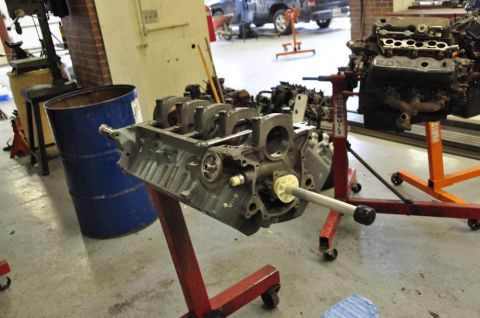 1996 Ford Bronco - An engine block is mounted on a red stand in a workshop, with another engine visible in the background.