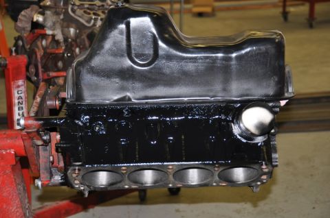 1996 Ford Bronco - A close-up view of an engine block and its oil pan, supported by a red engine stand.