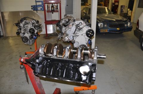 1996 Ford Bronco - Multiple engines and an engine block are displayed in a garage setting, with a blue car visible in the background.