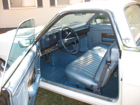 1969 Ford Ranchero - The interior of a 1969 Ford Ranchero shows blue seats and dashboard with the driver's door open.