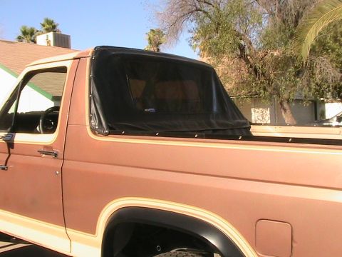 1985 Ford Bronco - Tan Ford Bronco with a black soft top installed over the bed area.
