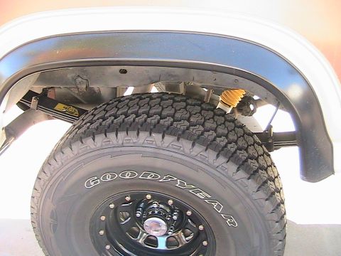 1985 Ford Bronco - The rear suspension and tire of a vehicle are visible, with a yellow shock absorber.