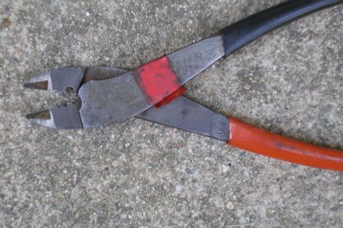 1997 Ford Taurus - Wire cutters with red and black handles resting on a concrete surface.