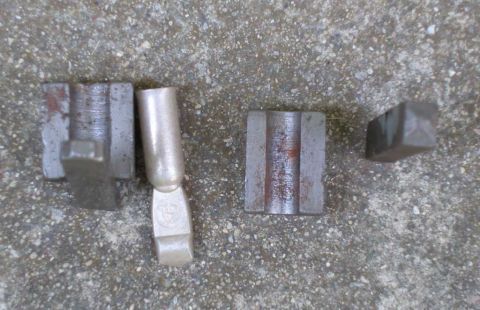 1997 Ford Taurus - Several metal electrical connectors are laid out on a concrete surface. One connector has a visible circular logo.