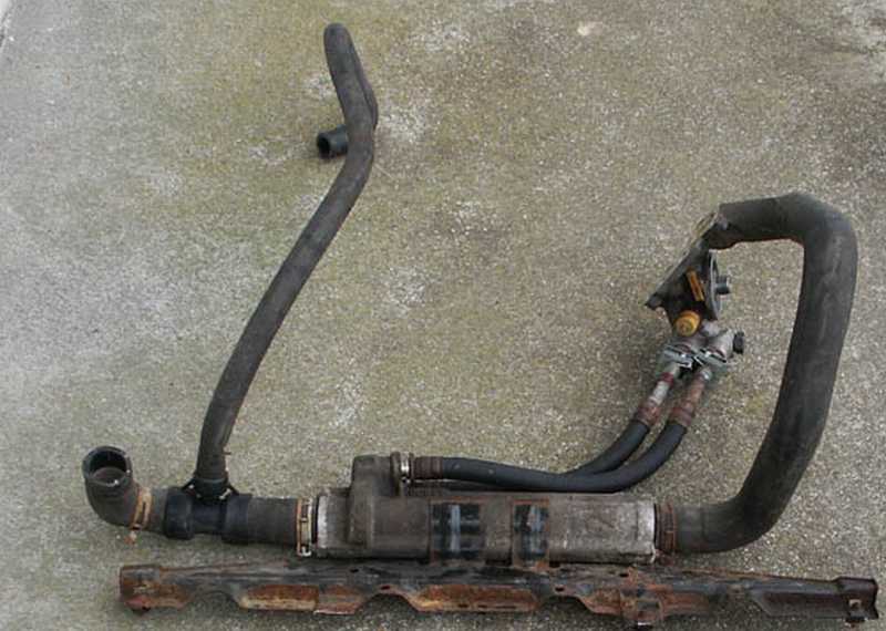 Transmission cooler assembly with rubber hoses attached, resting on a metal bracket