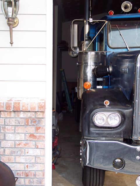 1981 Kenworth W900A - Front view of a large truck's cab, partially obscured by a garage opening and exterior wall.