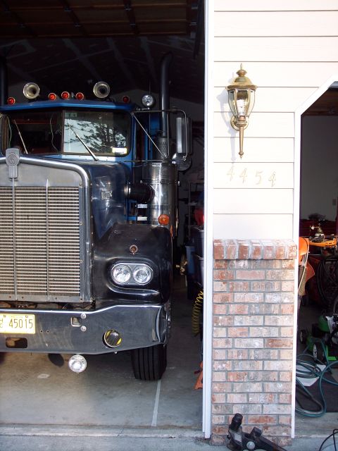 1981 Kenworth W900A - Front view of a blue semi-truck parked inside a garage, showing its grille, headlights, and exhaust stack.