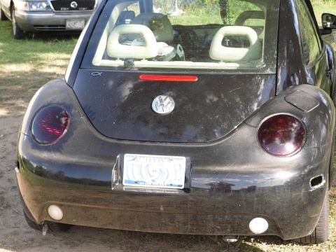 1999 Volkswagen Beetle - Rear view of a black 1999 Volkswagen Beetle parked outdoors with another car in the background.