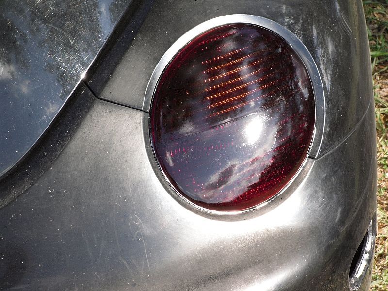 Close-up of a dark red taillight assembly on a gray car body