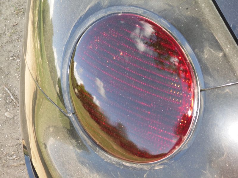 Close-up of a car's red taillight with a chrome ring