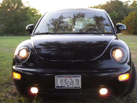 1999 Volkswagen Beetle - The front of a black Volkswagen Beetle is shown with its headlights and fog lights illuminated.