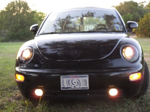 1999 Volkswagen Beetle - A black Volkswagen Beetle is parked outdoors, facing the camera with its headlights and fog lights illuminated.