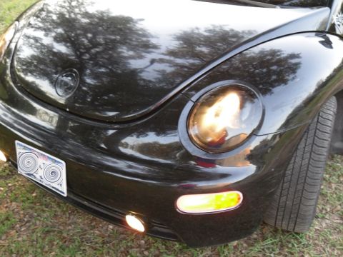 1999 Volkswagen Beetle - Front view of a black 1999 Volkswagen Beetle, showing its distinctive headlights and turn signals.