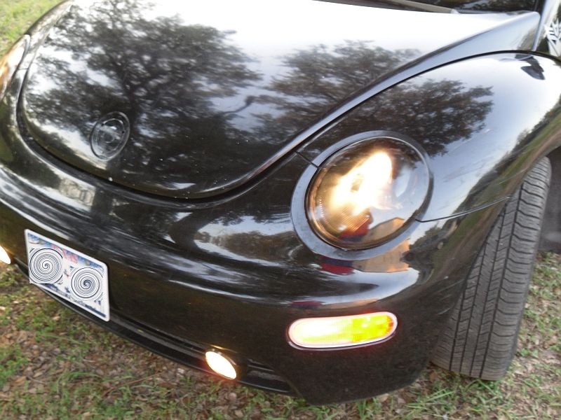Black 1999 Volkswagen Beetle front view with headlights on