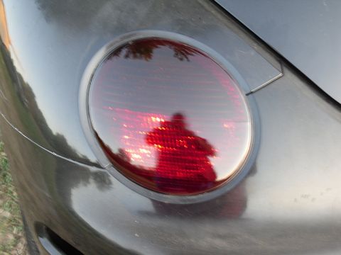 1999 Volkswagen Beetle - Car taillight detail, reflection of photographer visible.